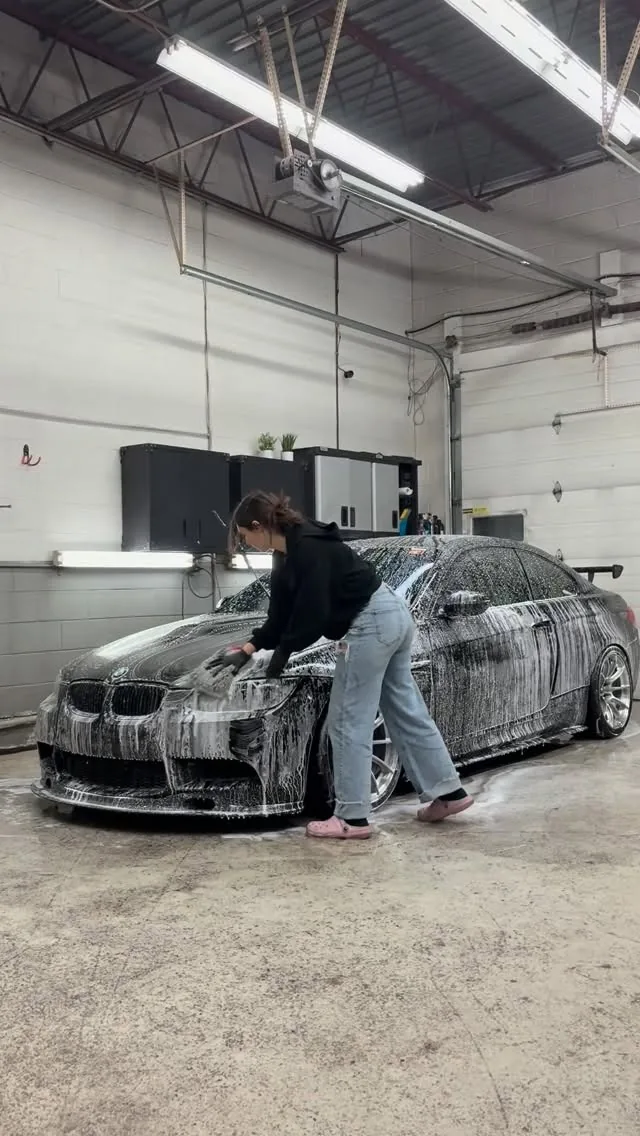 Cloud Shine owner hand foam washing a BMW M3 in the shop